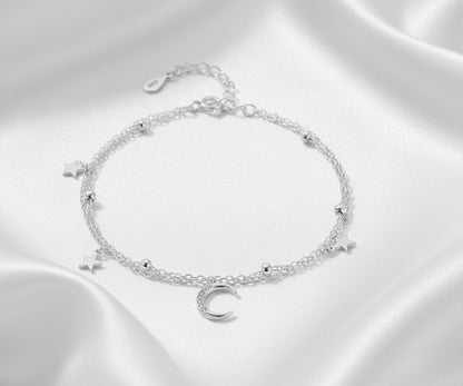 Silver bracelet with star and moon charms on a white background
