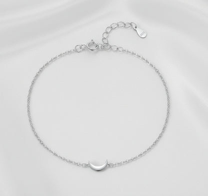 Silver bracelet with a moon charm on a white background