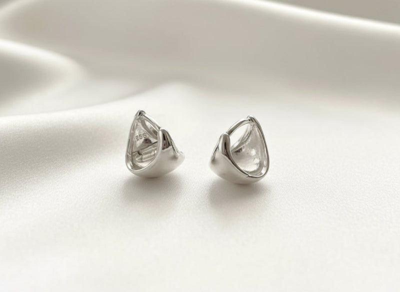Pair of silver teardrop-shaped earrings on a white background