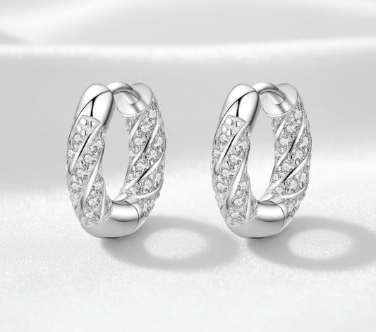 Pair of silver hoop earrings with diamond-like stones on a white background