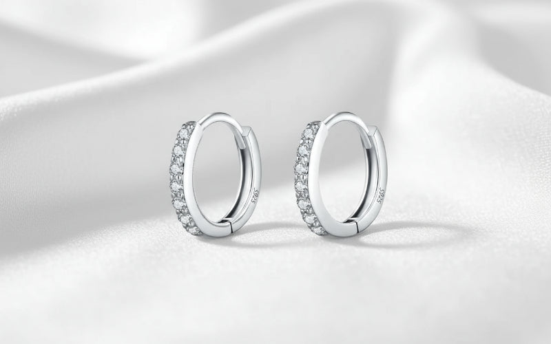 Silver hoop earrings with embedded stones on a white background