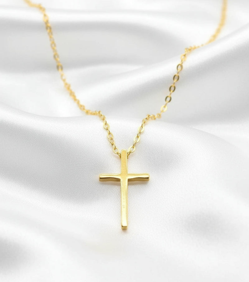 Gold cross necklace on a white satin background