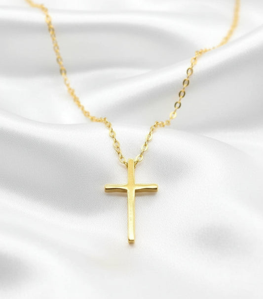 Gold cross necklace on a white satin background