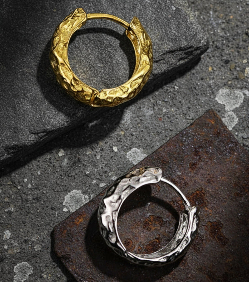Gold and silver hoop earrings on a dark textured background