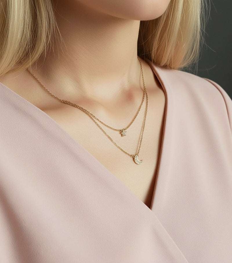 Close-up of a person wearing two gold necklaces with a white blouse.