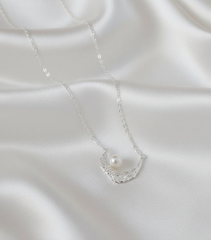 Pearl necklace on a white satin background