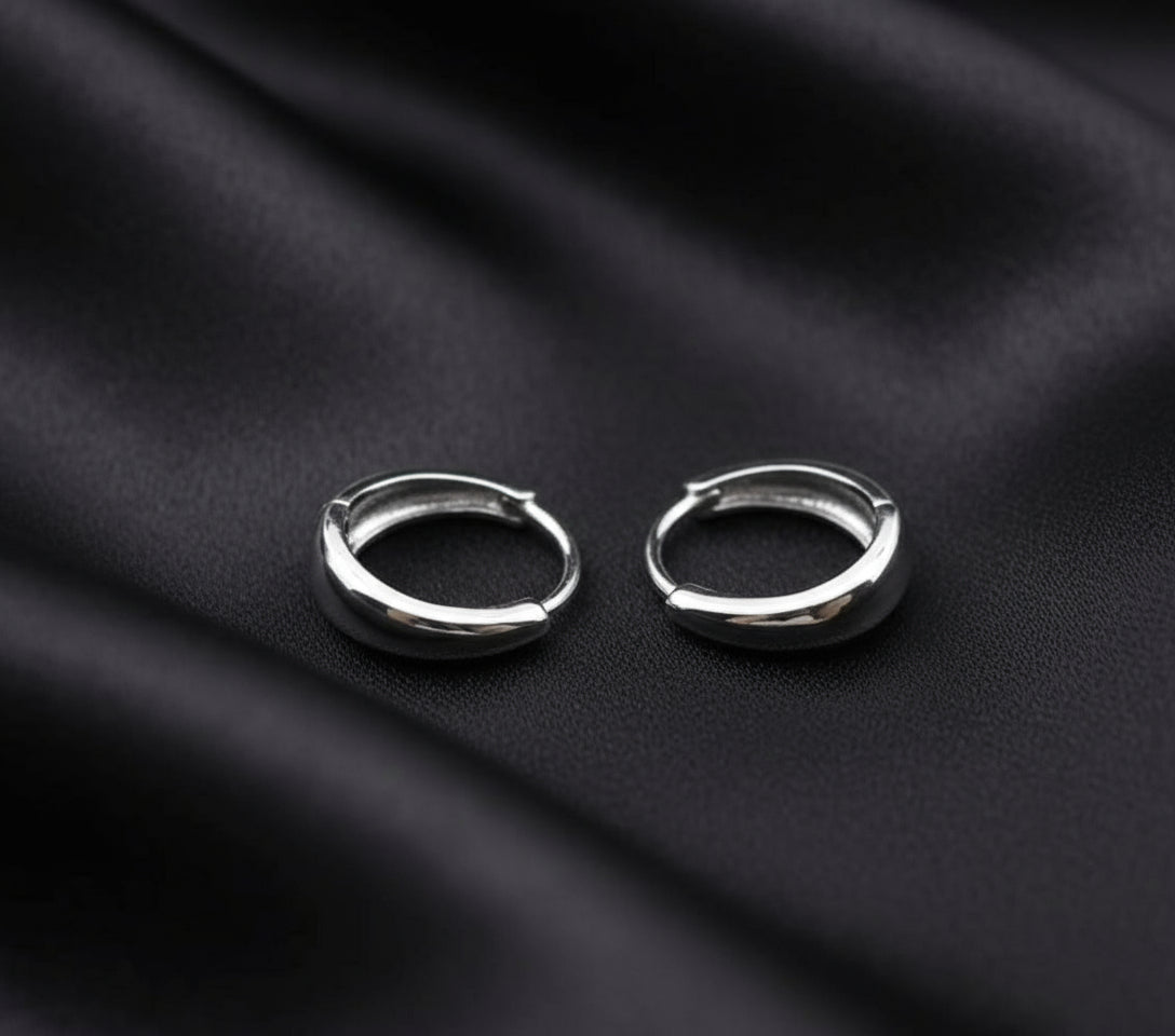 Two silver hoop earrings on a gray background