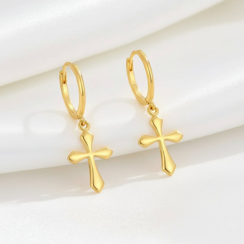 Gold cross earrings on a light background
