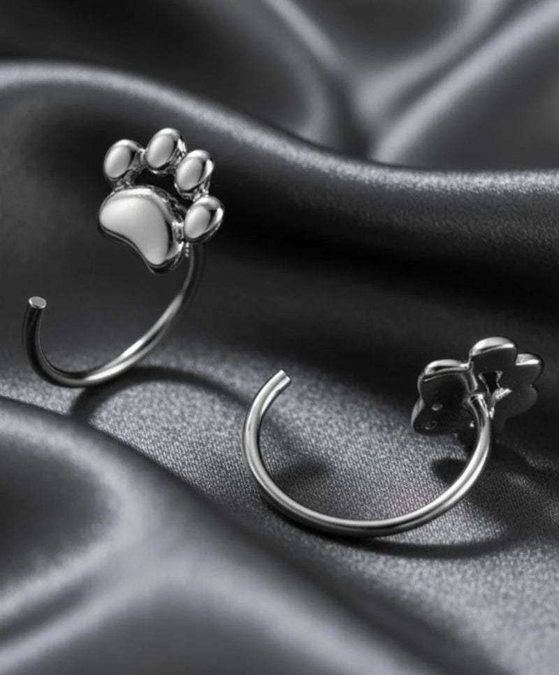 Silver paw print earrings on a dark background