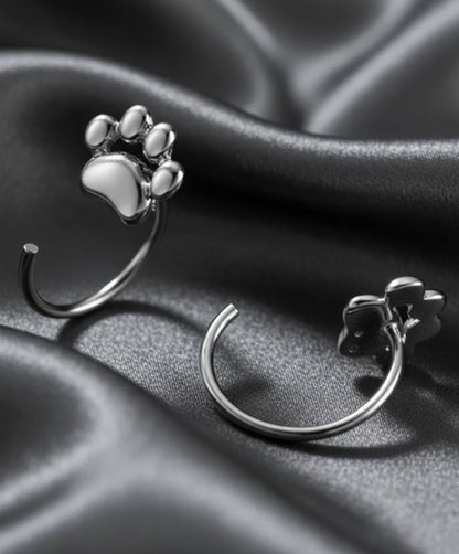 Silver paw print earrings on a dark background