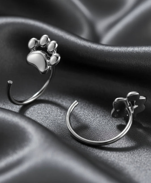 Silver paw print earrings on a dark background