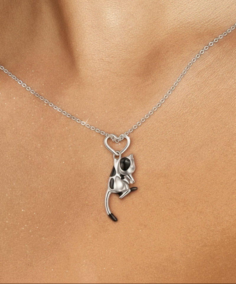 Silver cat-shaped pendant on a chain against a skin background