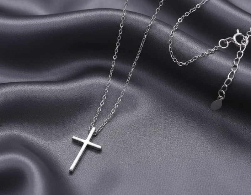 Silver cross necklace on a gray fabric background