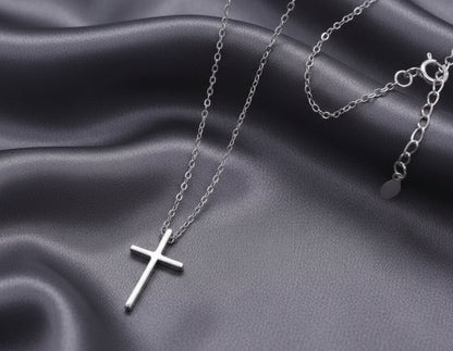 Silver cross necklace on a gray fabric background