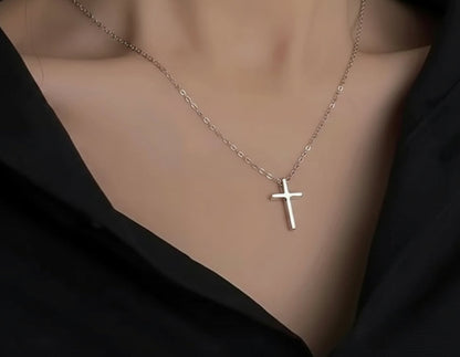 Silver cross necklace on a mannequin with a dark background