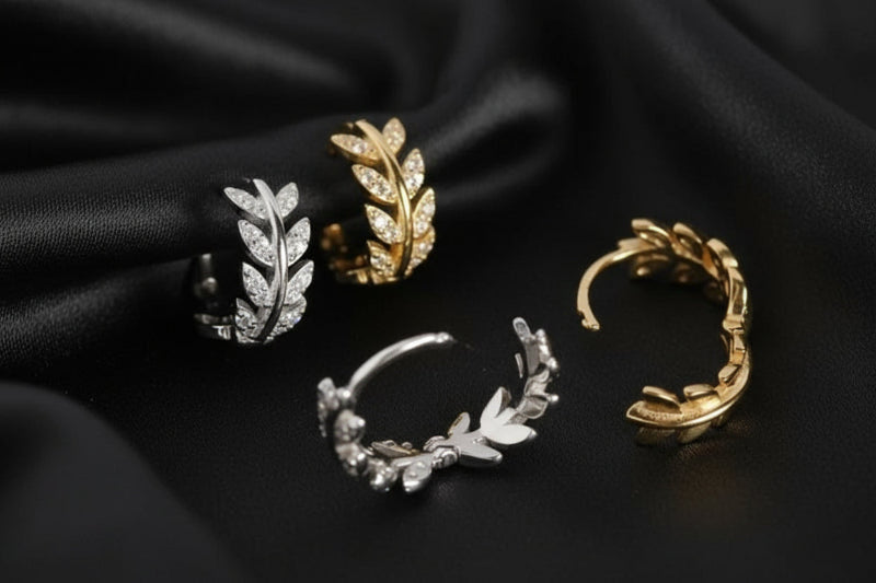 Four gold and silver leaf-shaped earrings on a white background
