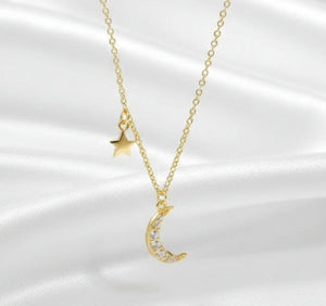 Gold necklace with moon and star pendants on a white background