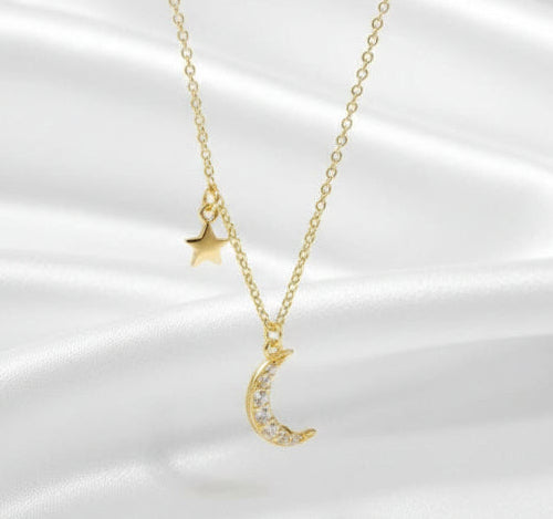 Gold necklace with moon and star pendants on a white background