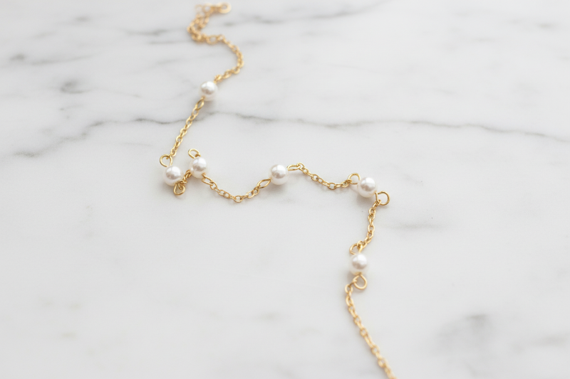 Gold necklace with pearls on white marble
