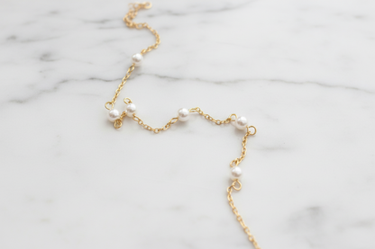 Gold necklace with pearls on white marble