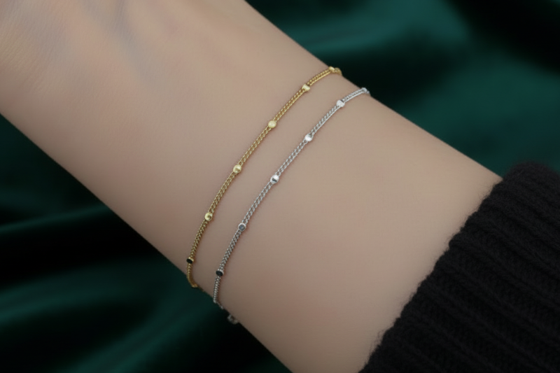 Two bracelets, one gold and one silver, on a wrist with a neutral background.