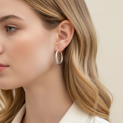 Silver hoop earring worn by a person with dark hair.