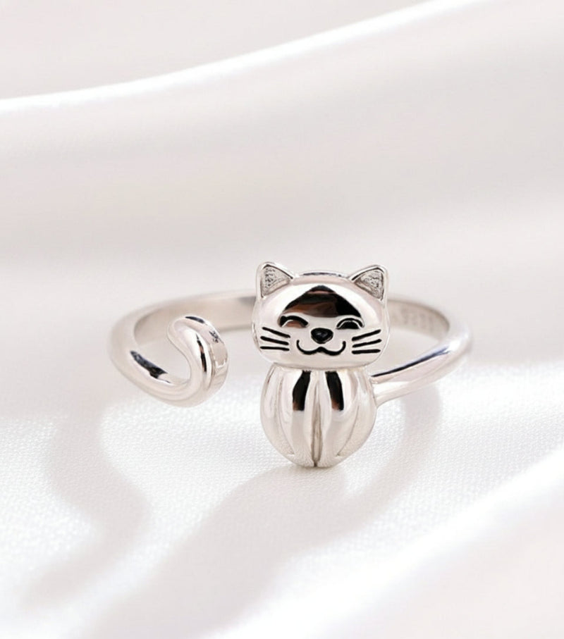 Silver cat-shaped ring on a white surface with a beige background
