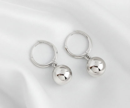 Pair of silver hoop earrings with round pendants on a white
 background