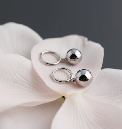 Pair of silver earrings on a white fabric background