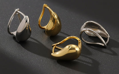 Four gold and silver rings on a textured grey surface
