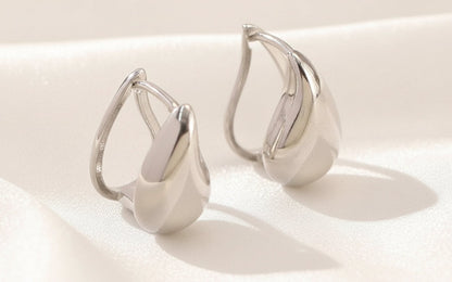 Pair of silver earrings on a textured white surface