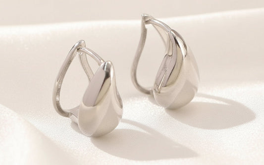 Pair of silver earrings on a textured white surface