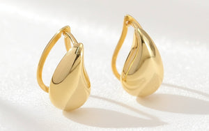 Pair of gold earrings on a textured white background