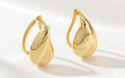 Pair of gold earrings on a textured white background