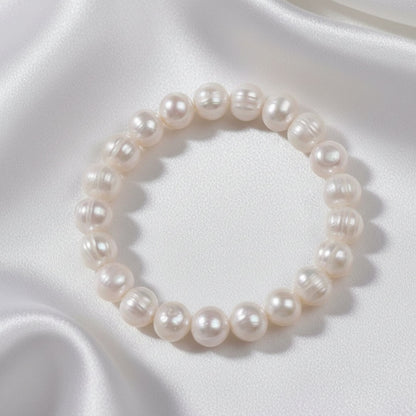 Pearl bracelet on a textured surface with a white fabric background