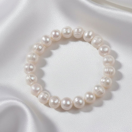 Pearl bracelet on a textured surface with a white fabric background