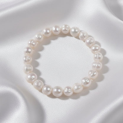 Pearl bracelet on white fabric in the background