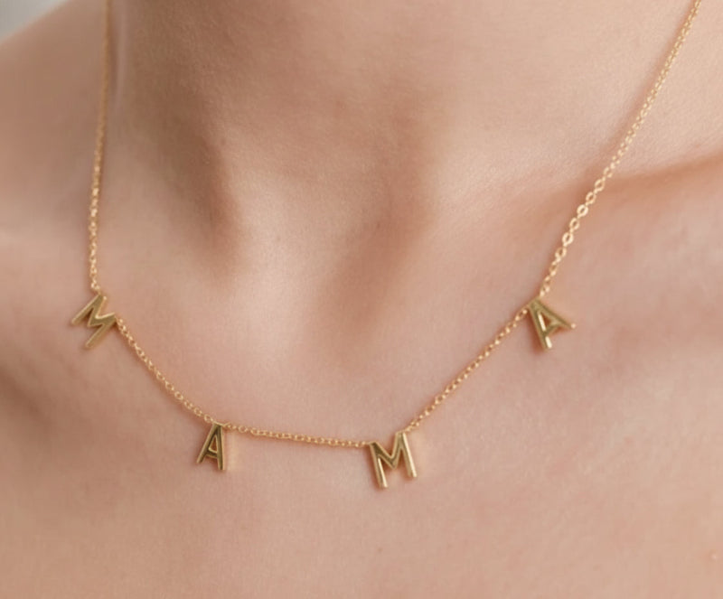 Gold necklace with 'MAMA' letters on a person's neck