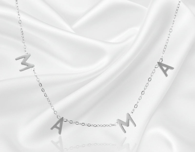 Silver necklace with 'MAMA' letters on a white fabric background