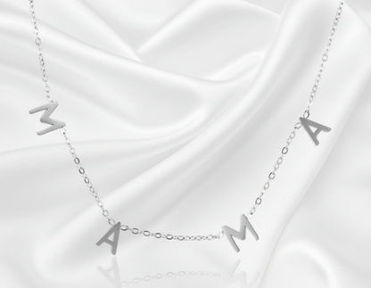 Silver necklace with 'MAMA' letters on a white fabric background