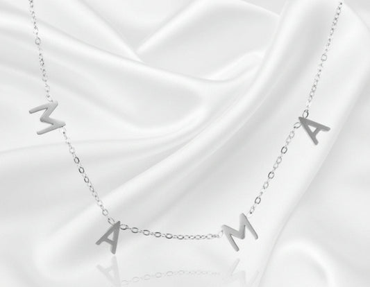 Silver necklace with 'MAMA' letters on a white fabric background