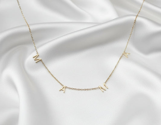Gold necklace with 'MAX' letters on a white background