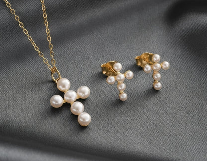 Pearl cross necklace and earrings on a pink fabric background