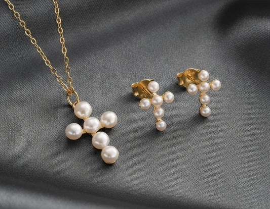 Pearl cross necklace and earrings on a pink fabric background