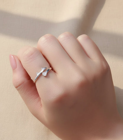 Hand wearing a silver ring with a leaf design on a blurred background