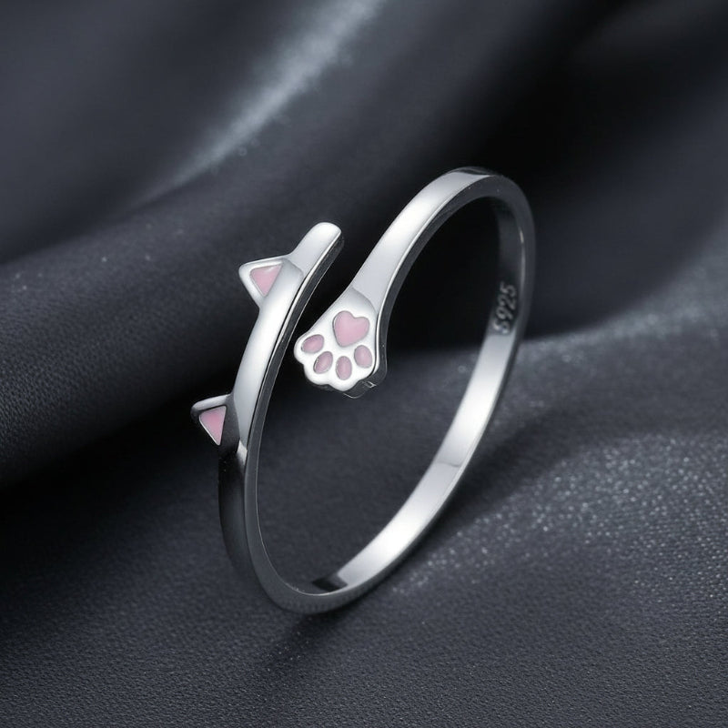 Silver ring with cat ear and paw design on a dark fabric background