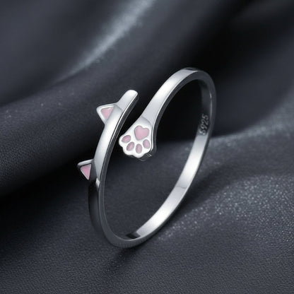 Silver ring with cat ear and paw design on a dark fabric background