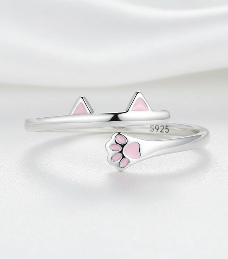 Silver ring with pink paw print design on a white background