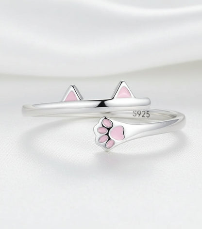 Silver ring with pink paw print design on a white background