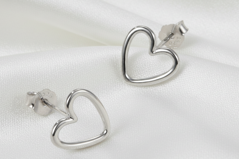 Silver heart-shaped earrings on a light beige background